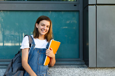 Portrait of smiling young woman holding book