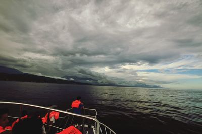 Boat sailing in sea against cloudy sky