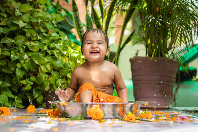 Cute toddler baby boy bathing in decorated bathtub at outdoor from unique perspective