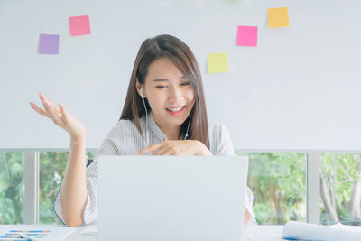 Portrait of young woman using phone while sitting on table