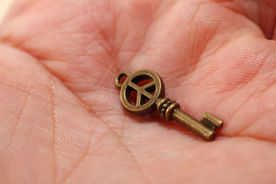 Close-up of human hand holding miniature antique key