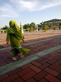 Rear view of woman walking on footpath