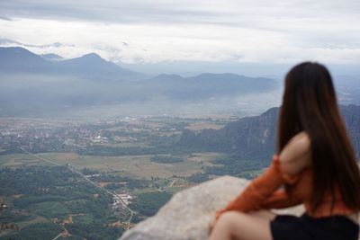 Rear view of woman looking at mountains against sky