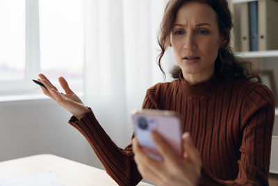 Worried woman gesturing while holding phone