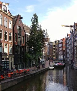 Canal amidst buildings in city against sky