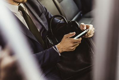 Midsection of businessman using smart phone while sitting in car