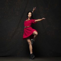 Full length of woman dancing on stage against black background