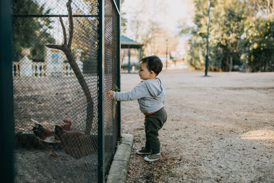 Full length of boy standing by fence