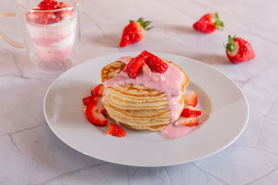 Close-up of dessert in plate on table. strawberry pancakes on white background.
