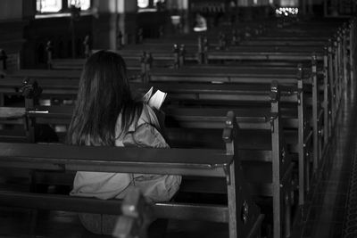 Rear view of woman sitting on bench in church