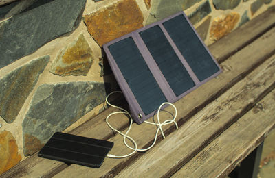 Close-up high angle view of smart phone and solar panels on wooden table