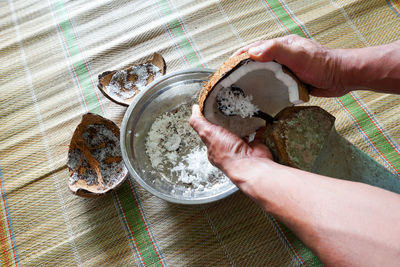 Cropped hands of man shredding coconut