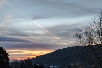 Low angle view of vapor trail in sky during sunset