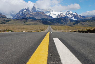 Empty road by mountains against sky