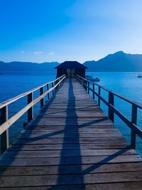 Pier over sea against clear blue sky