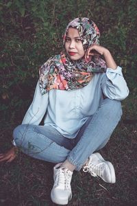 Portrait of a young woman sitting on field