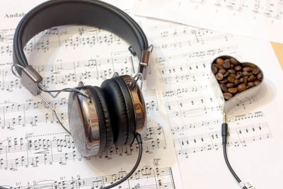 High angle view of headphones with coffee beans and sheet music on table