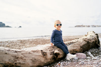 Side view of man sitting on rock at beach