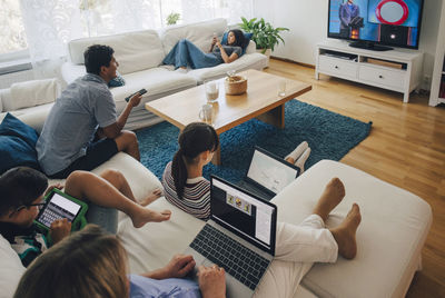 High angle view of family using technologies while relaxing in living room at home