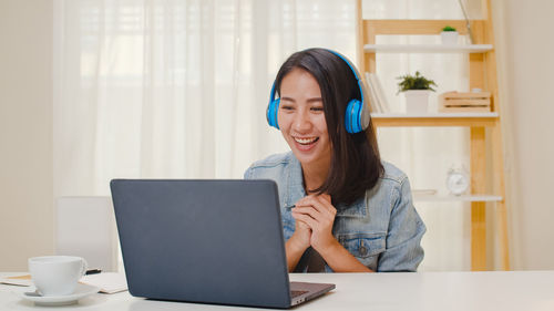 Young woman using phone while sitting on table