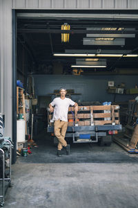 Portrait of carpenter leaning on pick-up truck at workshop