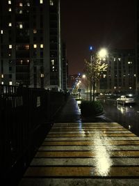Illuminated street amidst buildings in city at night