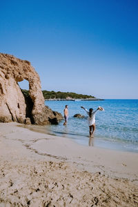 People on beach against clear blue sky