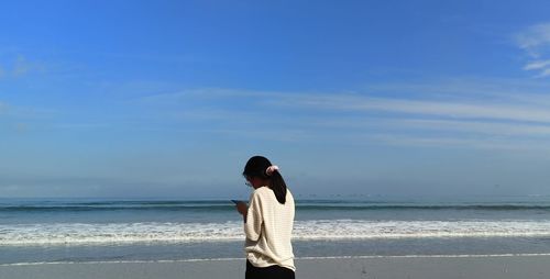 Man standing at beach against sky