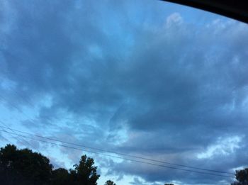 Low angle view of electricity pylon against cloudy sky