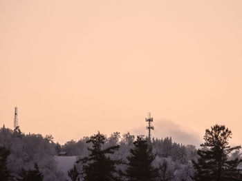 Silhouette trees and tower against sky during sunset