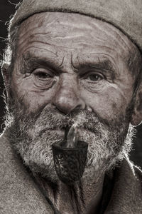 Close-up portrait of senior man smoking pipe