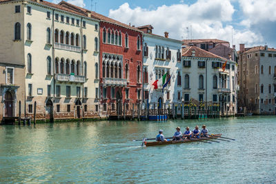 People rowing boat in grand canal against buildings
