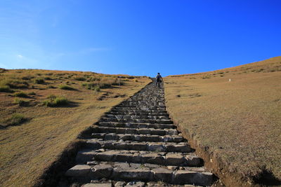 Man walking on steps against blue sky