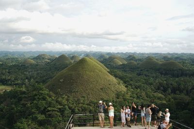 People looking at mountain range against sky