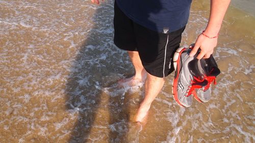 Low section of man standing on beach