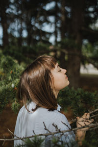 Full length of woman looking at tree in forest