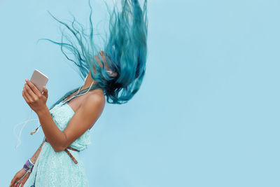 Midsection of woman drinking water against blue background