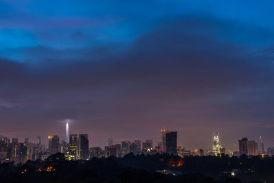 Illuminated buildings in city against sky at night