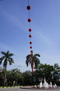 Street light hanging against trees against sky