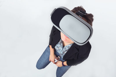 Woman using vr glasses while standing against gray background