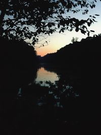 Reflection of silhouette trees on water against sky