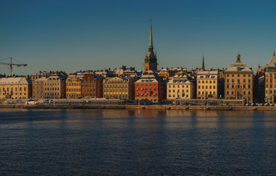 Buildings by river against clear sky