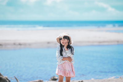 Woman standing at beach against sky