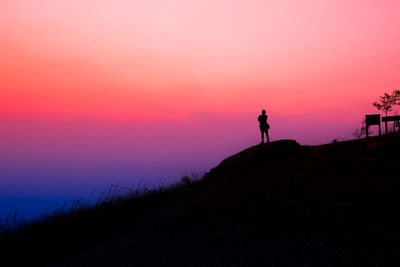 Silhouette man standing on shore against sky during sunset