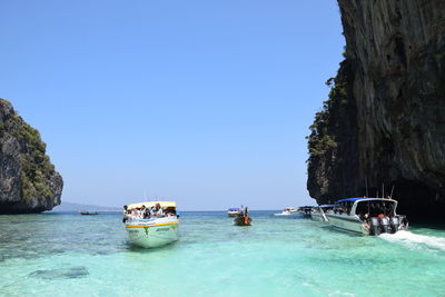 Boats sailing on sea against clear blue sky