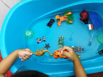 High angle view cropped hands of boy playing with toys in tub