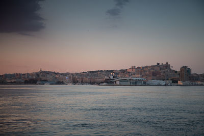 Town by sea against sky at sunset