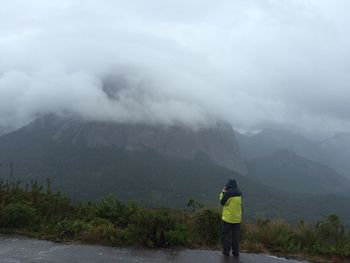 Rear view of woman standing on mountain against sky