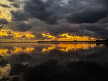 Scenic view of lake against cloudy sky during sunset