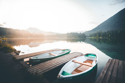 Boats moored at scenic lake against sky